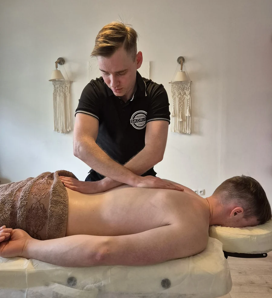 Illia Skoriak wykonuje masaż pleców klientowi w gabinecie Skoriak Massage Studio na Podgórzu w Krakowie
